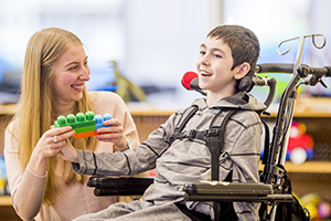 A caregiver interacting with a boy in a wheel chair