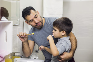 A father helping his son brush his teeth