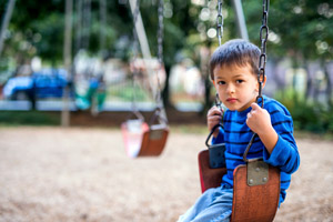 A young boy playing on a swing in a park.