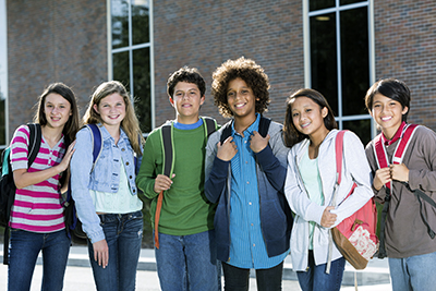 smiling group of tweens and teens with backpacks