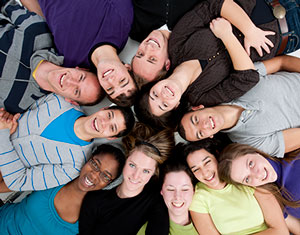 Grupo de jóvenes adultos acostado en un círculo y sonriendo